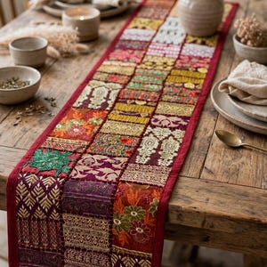 May include: A rectangular table runner featuring a patchwork design of various fabric squares in shades of red, gold, purple, and green. The runner is decorated with intricate embroidery, metallic thread accents, and floral patterns throughout.