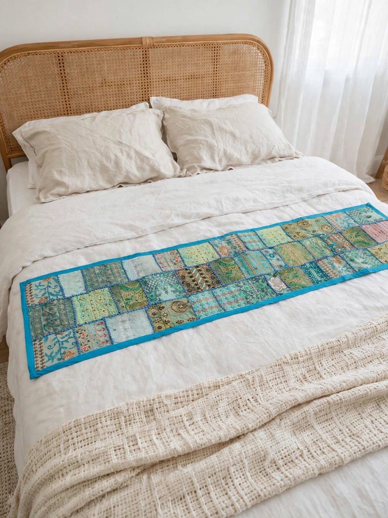 Puede incluir: Un camino de cama rectangular con un dise&ntilde;o de parches de varios cuadrados de tela en tonos verdes y azulados, con bordados intrincados y detalles de hilo met&aacute;lico, acabado con un borde de color azul brillante en todo el contorno.