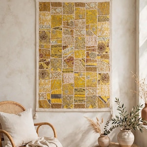 May include: A rectangular wall hanging featuring a patchwork design of various yellow and gold fabric squares. The textile displays diverse patterns, including floral and geometric motifs, with visible white stitching between each square.