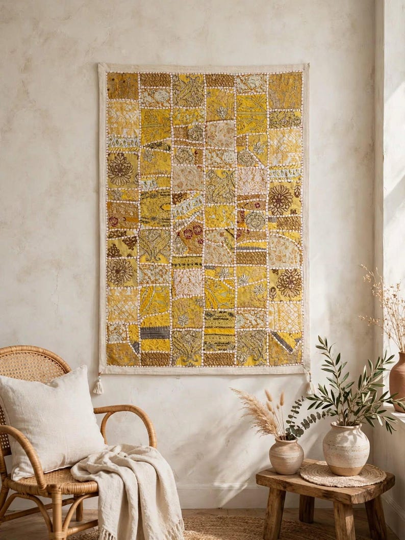 May include: A rectangular wall hanging featuring a patchwork design of various yellow and gold fabric squares. The textile displays diverse patterns, including floral and geometric motifs, with visible white stitching between each square.