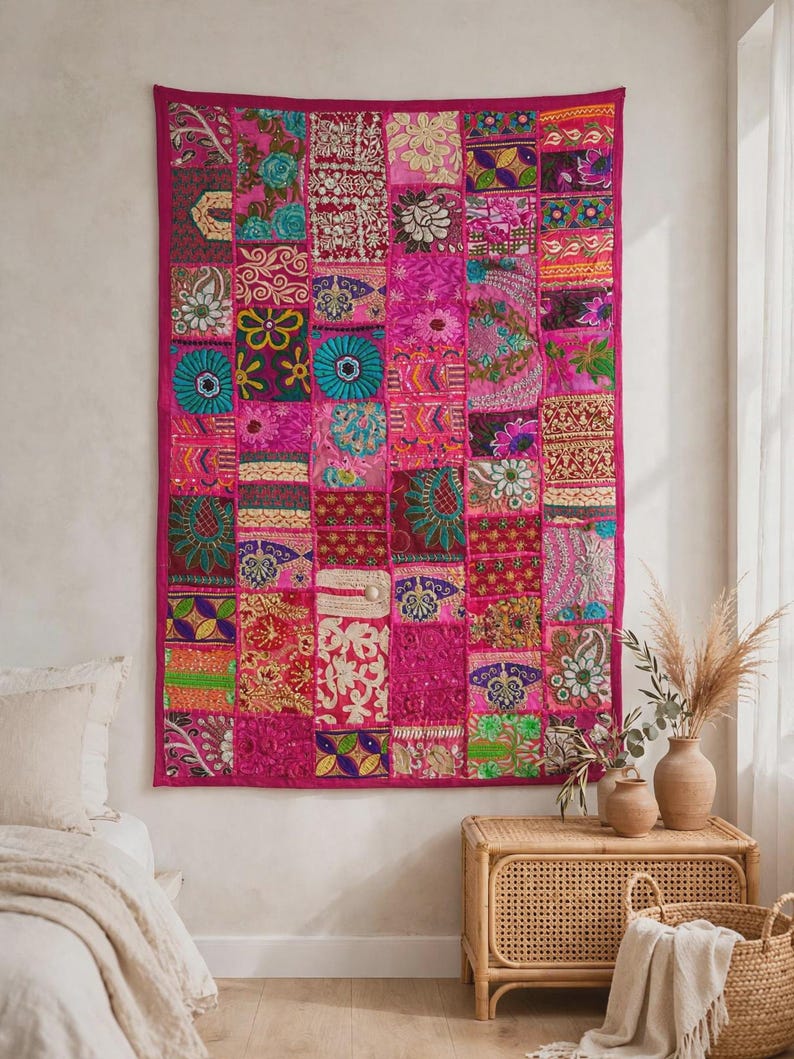 May include: A rectangular wall hanging featuring a patchwork design of various fabric squares in shades of hot pink, magenta, teal, gold, and green. The textile displays intricate embroidery, floral patterns, and geometric shapes throughout.