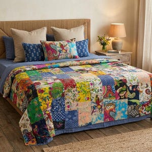 May include: A bed featuring a patchwork quilt with a vibrant, multi-colored floral and paisley pattern. The bedding includes two large beige square pillows, two smaller blue patterned pillows, and one rectangular pillow with a colorful print.