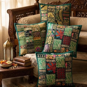 May include: Four square throw pillows featuring a patchwork design of green fabric panels with intricate gold, red, and blue embroidery. Each pillow displays a variety of floral and geometric patterns stitched onto the surface in a grid layout.
