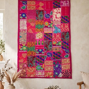 May include: A rectangular wall hanging featuring a vibrant patchwork design of various fabric squares in shades of hot pink, magenta, gold, green, and blue. The textile displays intricate embroidery, metallic thread accents, and floral patterns.