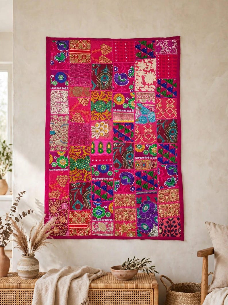 May include: A rectangular wall hanging featuring a vibrant patchwork design of various fabric squares in shades of hot pink, magenta, gold, green, and blue. The textile displays intricate embroidery, metallic thread accents, and floral patterns.