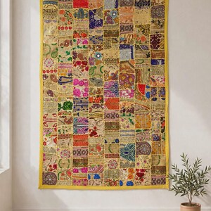 May include: A rectangular wall hanging featuring a patchwork design of various fabric squares in diverse colors including gold, red, blue, and pink. The textile is bordered by a solid yellow trim and displays intricate embroidery and small mirrors.