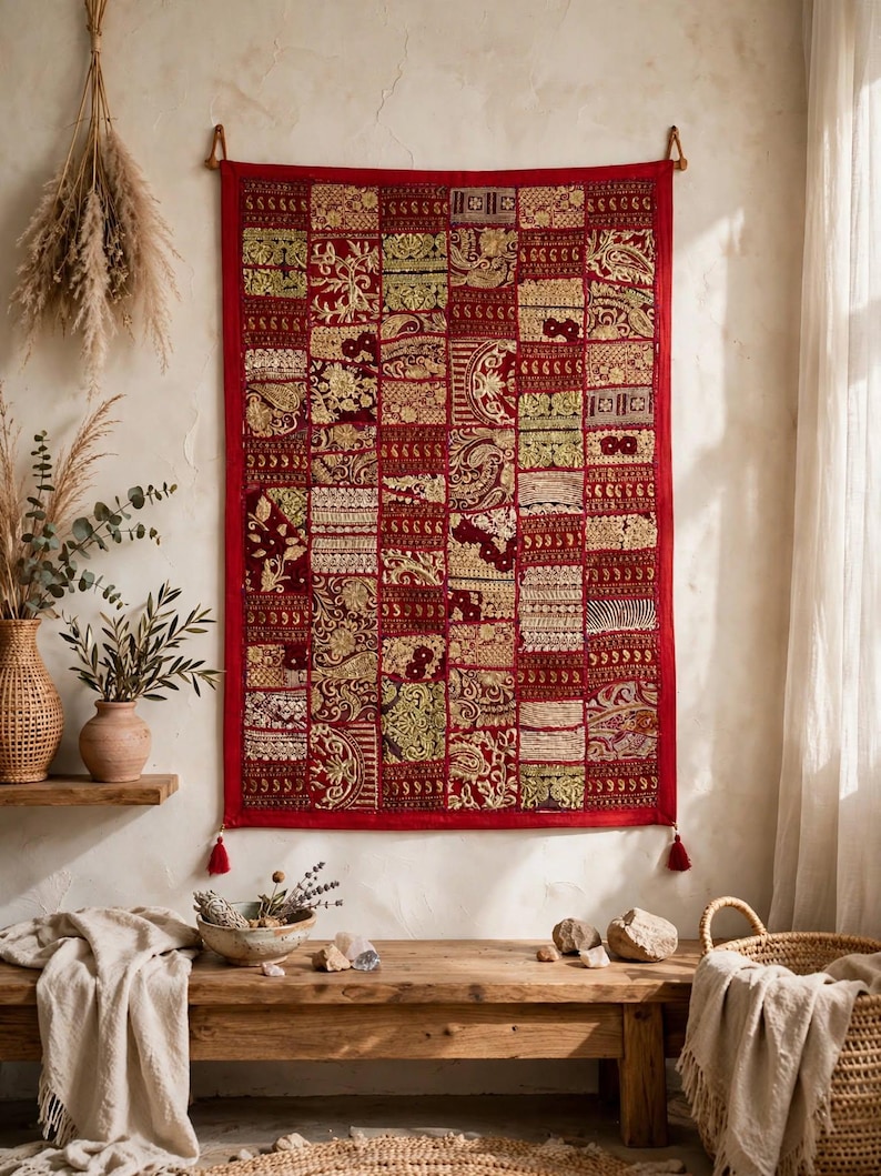 May include: A rectangular wall hanging featuring a patchwork design of deep red fabric squares. Each square is decorated with intricate gold-colored embroidery, metallic thread patterns, and floral motifs. The piece has a red border and two tassels.