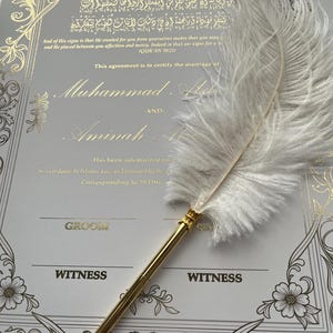 May include: A wedding certificate with gold calligraphy and floral accents. The text includes names and a quote. A white feather pen with a gold barrel rests on the certificate, ready to sign the marriage agreement.