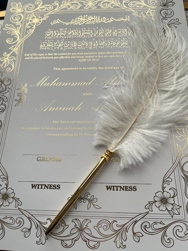 May include: A wedding certificate with gold calligraphy and floral accents. The text includes names and a quote. A white feather pen with a gold barrel rests on the certificate, ready to sign the marriage agreement.