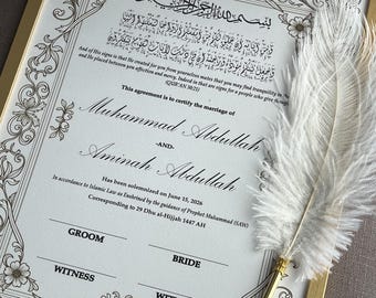 May include: A framed marriage certificate with ornate floral and scrollwork borders. The document, in English and Arabic, certifies the marriage of Muhammad Abdullah and Aminah Abdullah. A white feather pen rests on the frame.