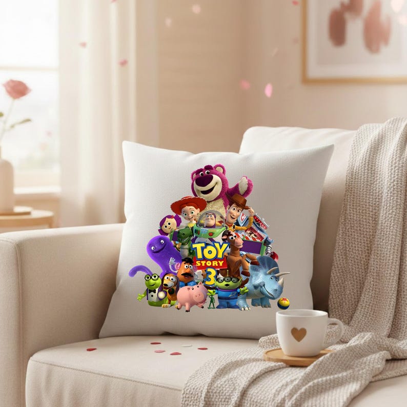 May include: White square pillow featuring a colorful graphic of characters from the animated film "Toy Story 3." The design includes Woody, Buzz Lightyear, and other beloved characters. The pillow is placed on a beige sofa.