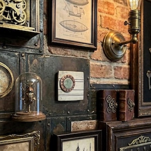 May include: A wall display featuring a collection of mechanical and vintage items, including a framed airship patent print, a brass wall lamp with an Edison bulb, a beetle specimen under a glass dome, and various framed clock parts and keys.