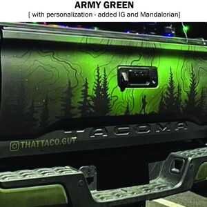 Puede incluir: Port&oacute;n trasero de cami&oacute;n verde militar con un dise&ntilde;o de escena de bosque. El dise&ntilde;o presenta siluetas negras de &aacute;rboles y una persona caminando, sobre un degradado de verde. El texto "TACOMA" es visible.