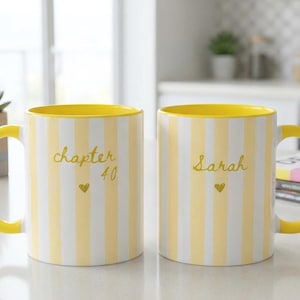 May include: Two ceramic mugs featuring vertical yellow and white stripes with a bright yellow interior and handle. One mug displays the text "chapter 40" with a small heart, while the other mug features the name "Sarah" with a small heart.