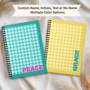 May include: Two spiral-bound notebooks with a gingham pattern. One is teal with the word "PEACE" in pink, and the other is yellow with the word "GRACE" in teal. The text "Custom Name, Initials, Text or No Name Multiple Color Options" is at the top.