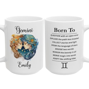 May include: A white ceramic mug featuring a Gemini zodiac illustration of two faces with flowing hair in gold and blue tones, the name Emily, and the text Born To QUESTION, EXPLORE, COLLECT, SPEAK, BRIDGE, MIRROR, WEAVE, ADAPT, and the Gemini symbol.