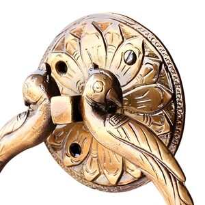 May include: A bronze-colored cabinet pull with a decorative bird design. The pull features two birds facing outward, with a circular backplate adorned with floral and leaf patterns. The hardware is made of metal and has a vintage aesthetic.