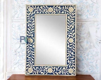 May include: A rectangular wall mirror featuring a dark blue frame with an intricate inlaid floral pattern in cream. The design consists of repeating vine and flower motifs surrounding the central reflective glass surface. The logo PGC Global is visible.