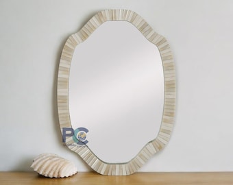 May include: An oval wall mirror featuring a frame composed of small, rectangular, off-white tiles arranged in a radial pattern. The mirror has a scalloped edge design. A small logo with the text PC GLOBAL EXPORTS is visible on the lower left side.