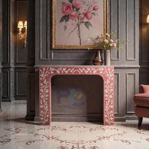 May include: A red marble fireplace with white floral inlay. The fireplace is set against a grey wall with a framed floral painting above. The floor has a matching floral pattern. A vase of flowers sits on the mantel.