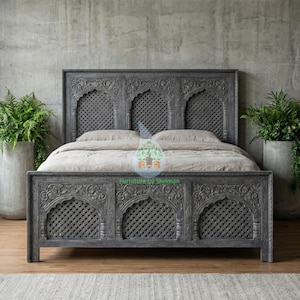 Può includere: Un letto in legno grigio con intagli intricati e un design a griglia. La testiera e la pediera presentano pannelli ad arco con un motivo geometrico. Il letto è posto contro un muro di cemento, con piante in vasi di cemento.