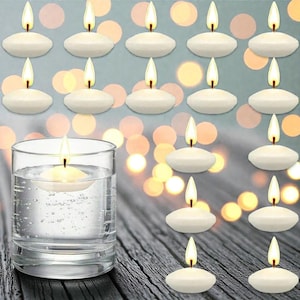 Peut inclure: Bougies flottantes avec des flammes allumées. Un verre transparent rempli d'eau contient une bougie flottante. D'autres bougies flottantes sont disposées sur une surface en bois. L'arrière-plan présente un effet bokeh avec des lumières douces et floues.