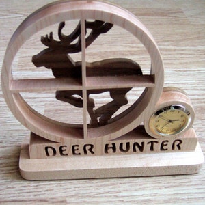 May include: Wooden deer hunter clock with a round clock face and the words "DEER HUNTER" inscribed on the base.