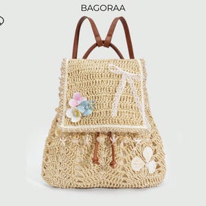 May include: A beige woven backpack with brown straps and a drawstring closure. The backpack features a flap with a white lace design and is adorned with faux flowers and shell accents. The word "BAGORAA" is printed at the top.
