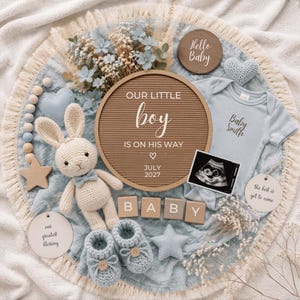 May include: A light blue baby announcement set featuring a round felt letter board with the text OUR LITTLE boy IS ON HIS WAY JULY 2027, a light blue onesie, a crocheted bunny, baby booties, wooden blocks spelling BABY, and an ultrasound image.