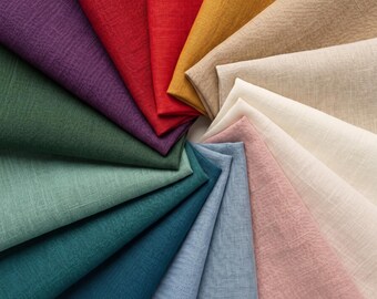 May include: A collection of folded fabric squares arranged in a circular fan pattern. The colors include purple, red, yellow, beige, cream, light pink, light blue, dark blue, teal, sage green, and dark green, all featuring a visible woven texture.