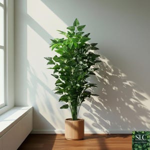 Puede incluir: Una planta verde artificial en una maceta de madera. La planta tiene muchas hojas pequeñas y puntiagudas y se coloca frente a una pared blanca. La maceta es cilíndrica con listones de madera verticales. La planta está cerca de una ventana.