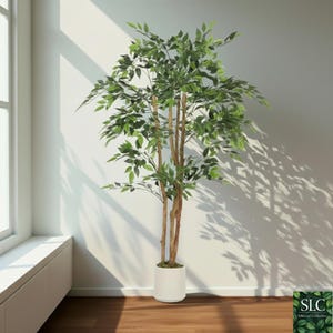 May include: An artificial tree with vibrant green foliage and brown stems, presented in a white cylindrical pot. The tree stands against a white wall, with natural light and shadows creating a realistic effect.