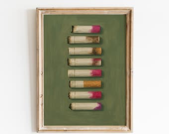 May include: A framed art print featuring a series of cigarette butts arranged vertically against a green background. The cigarette filters display shades of pink, orange, and purple. The frame has a gold-colored finish.