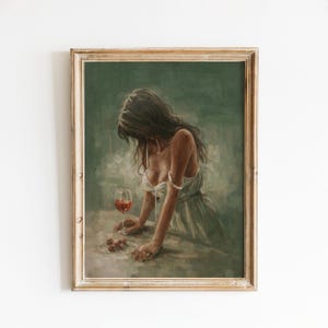 May include: A framed art print depicts a woman with long dark hair, leaning on a table. A glass of red wine and a few cherries are on the table. The artwork has a vintage aesthetic with a muted color palette.