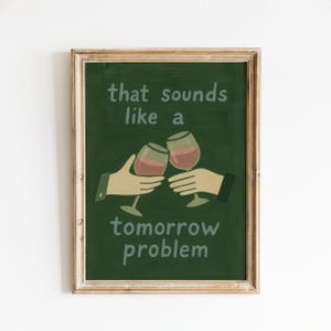 May include: A framed print with a dark green background and the text "that sounds like a tomorrow problem." Two hands are depicted toasting with wine glasses filled with red wine. The frame is a light brown color.