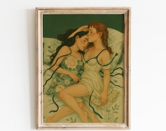 May include: A framed art print depicts two women in a tender embrace, resting on a floral-patterned bed. One woman wears a floral dress, the other a white slip. The artwork features soft colors and flowing lines, creating a serene and intimate scene.