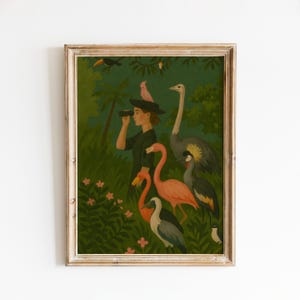 May include: A framed art print depicts a person observing birds with binoculars in a lush, green jungle setting. The artwork features a variety of colorful birds, including flamingos, a toucan, and a crowned crane. The overall aesthetic is vintage and whimsical.
