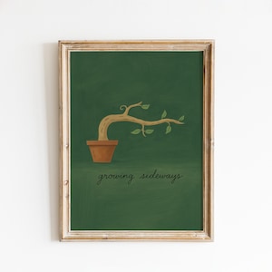 May include: Framed art print featuring a stylized illustration of a plant growing sideways. The plant is in a brown pot against a dark green background. The text "growing sideways" is written in cursive below the pot.