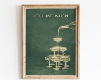 May include: A framed print with a green background and the text "TELL ME WHEN". The image depicts a champagne bottle pouring into a pyramid of champagne glasses. The frame is a light brown color.