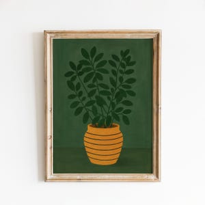 May include: A framed art print featuring a stylized illustration of a potted plant. The plant has dark green leaves and sits in a yellow-orange pot with horizontal black stripes. The background is a solid dark green color.