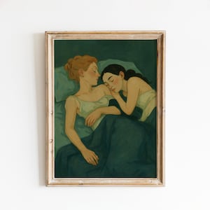 May include: A framed art print depicts two figures in a bed, one with auburn hair and the other with dark hair, both in a deep green setting. The artwork has a soft, painterly style, with muted colors and a focus on intimacy.