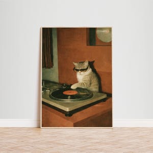 May include: A framed print featuring a tabby cat wearing sunglasses, operating a vintage turntable. The cat is positioned in front of a red-brown background. The turntable has a black vinyl record with an orange center.