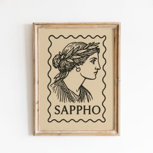 May include: Framed print featuring a black and white illustration of Sappho, a Greek poet, in profile. The image is set against a beige background within a postage stamp-style border. The name "SAPPHO" is printed below the image.