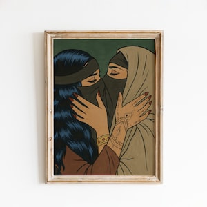May include: A framed art print featuring two figures embracing. One figure has dark blue hair and a black face covering, the other wears a tan hijab. The artwork has a pop art style with bold lines and a green background.