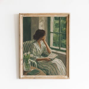 May include: A framed oil painting depicting a person with dark hair sitting in a striped armchair by a window. The person wears a matching striped robe and holds an open book. A glass vase with white tulips sits on a table with a green book.