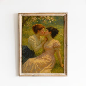 May include: A framed painting depicts two women in a tender embrace. One, with auburn hair, wears a cream-colored blouse and navy skirt. The other, with dark hair, is in a pink dress. They are in a grassy field under a flowering tree.