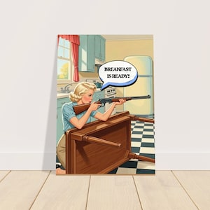 May include: A retro-style print depicts a woman aiming a rifle over a wooden table in a kitchen. A speech bubble above her says, "BREAKFAST IS READY!" The kitchen has light blue cabinets, a window with red curtains, and a black and white checkered floor.