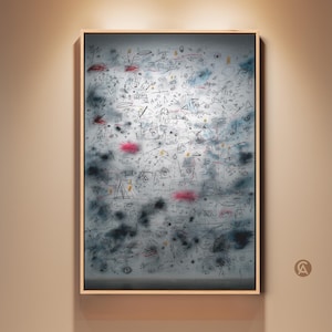 May include: Abstract artwork in a light wooden frame. The artwork features a gray background with black and blue scribbles, shapes, and pink accents. The painting is mounted on a beige wall and illuminated by a spotlight.