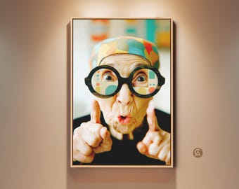 Könnte beinhalten: Gerahmter Kunstdruck mit einer älteren Person mit großer, runder, schwarz umrandeter Brille. Die Brille hat farbenfrohe geometrische Muster. Die Person trägt eine gemusterte Kopfbedeckung und schwarze Kleidung, wobei die Finger nach oben zeigen.