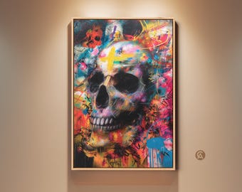 Puede incluir: Una obra de arte enmarcada que presenta una calavera colorida. La calavera está pintada con una mezcla de colores brillantes, incluyendo rosa, azul, amarillo y naranja. Una cruz amarilla está pintada en la frente. La obra se exhibe en una pared beige.